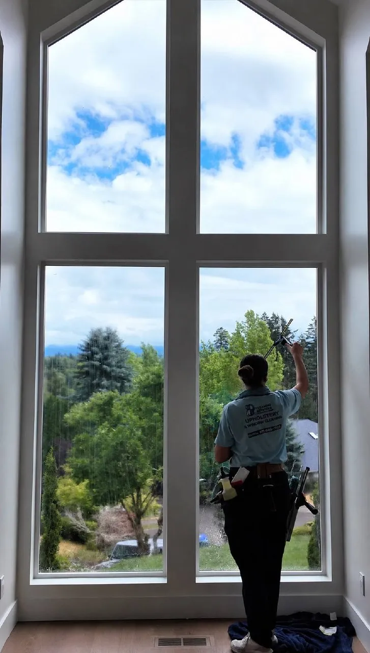 AB Cleaning Services NW cleaning a tall residential window to a streak-free shine